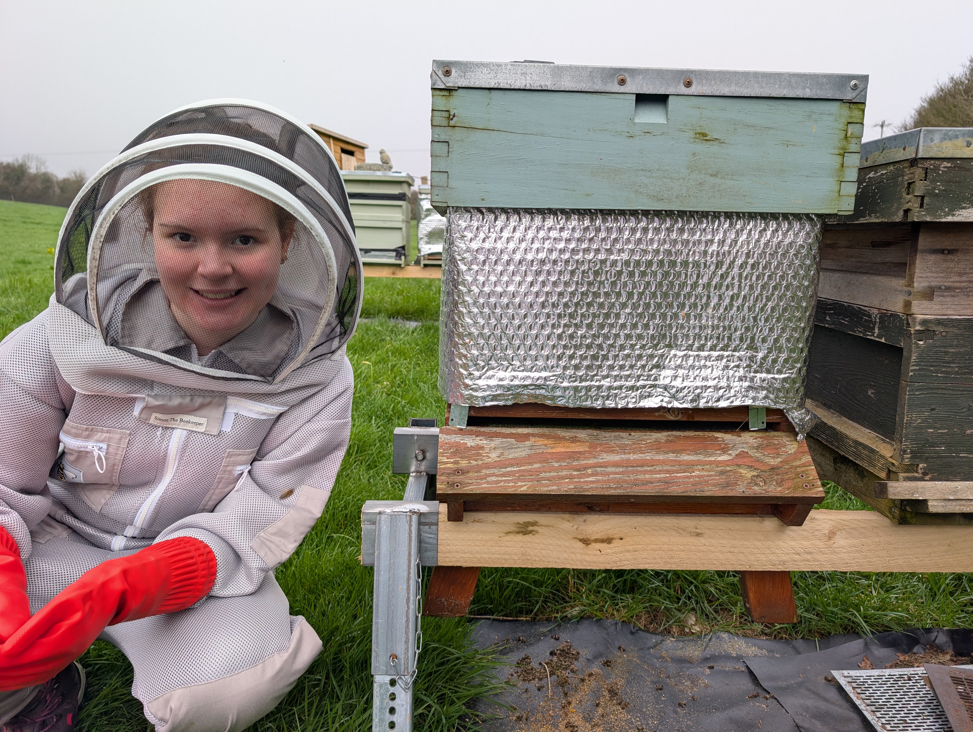 Tilly Culshaw in a bee suit inspecting a hive — the next generation of UK beekeepers